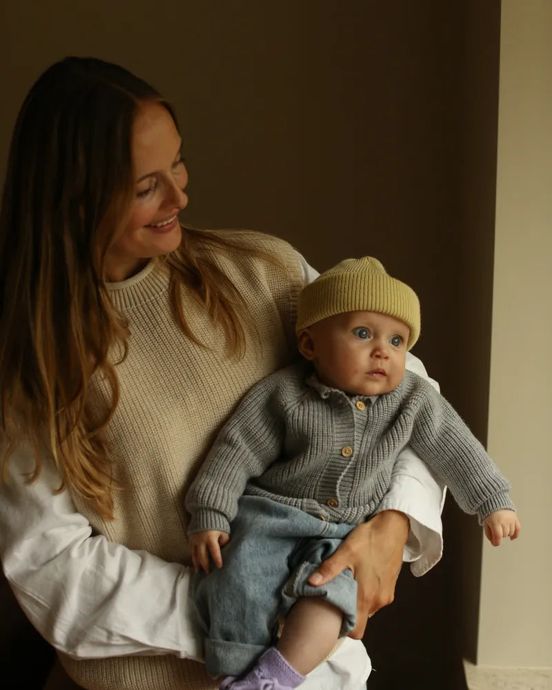 Mama trzyma niemowlę w kardiganie z wełny merino