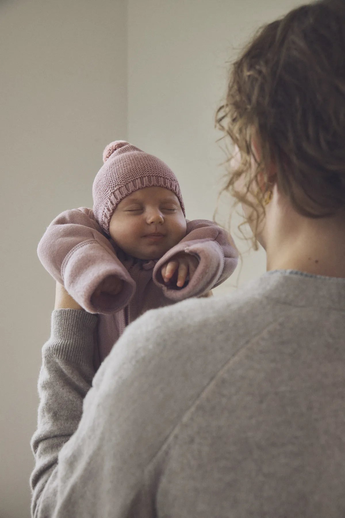 Mama trzyma niemowlę w wełnianym ubranku i czapce