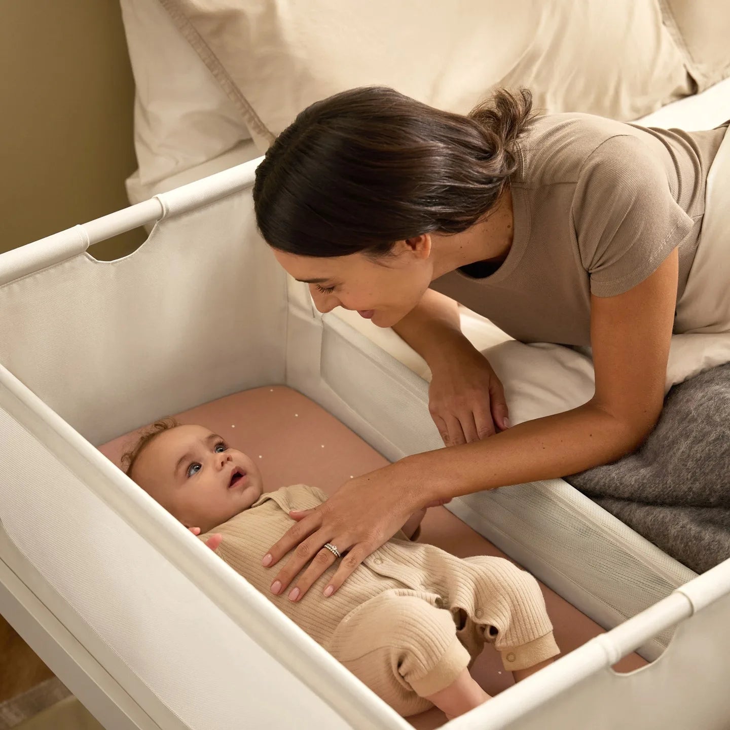 Mama pochyla się nad niemowlęciem w łóżeczku dostawnym SnuzPod5